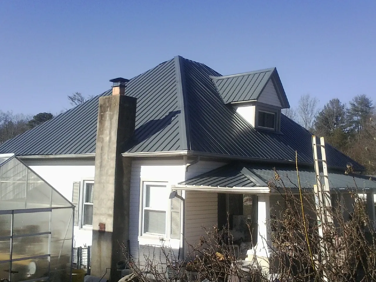 Dark blue standing seam metal roof on a white farmhouse with dormer — Slate & Tile Roof Repair by Roofing Brothers in Cataldo