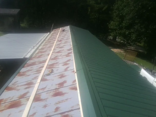 Old rusted panels beside newly installed green metal roofing — Wind Damage Roof Repair by Roofing Brothers in Cataldo