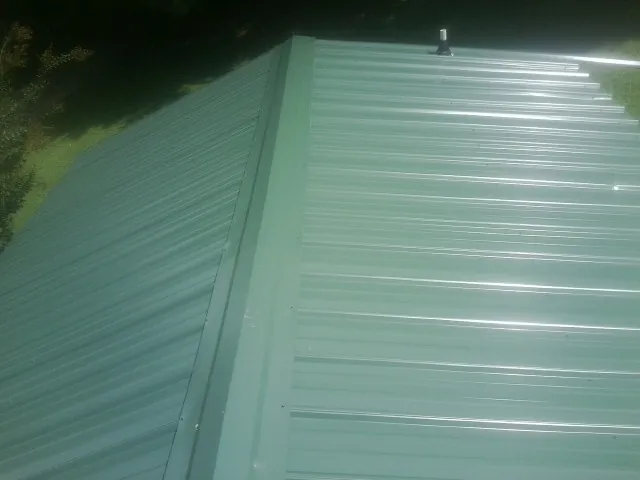 New green metal panels meeting at the ridge of a roof — Flat Roof Repair work by our crew in Cataldo
