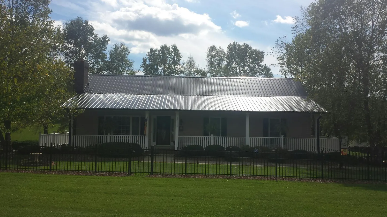 Gray metal roof on a brick ranch with a full width front porch — Gutter Guard Installation work by our crew in Cataldo