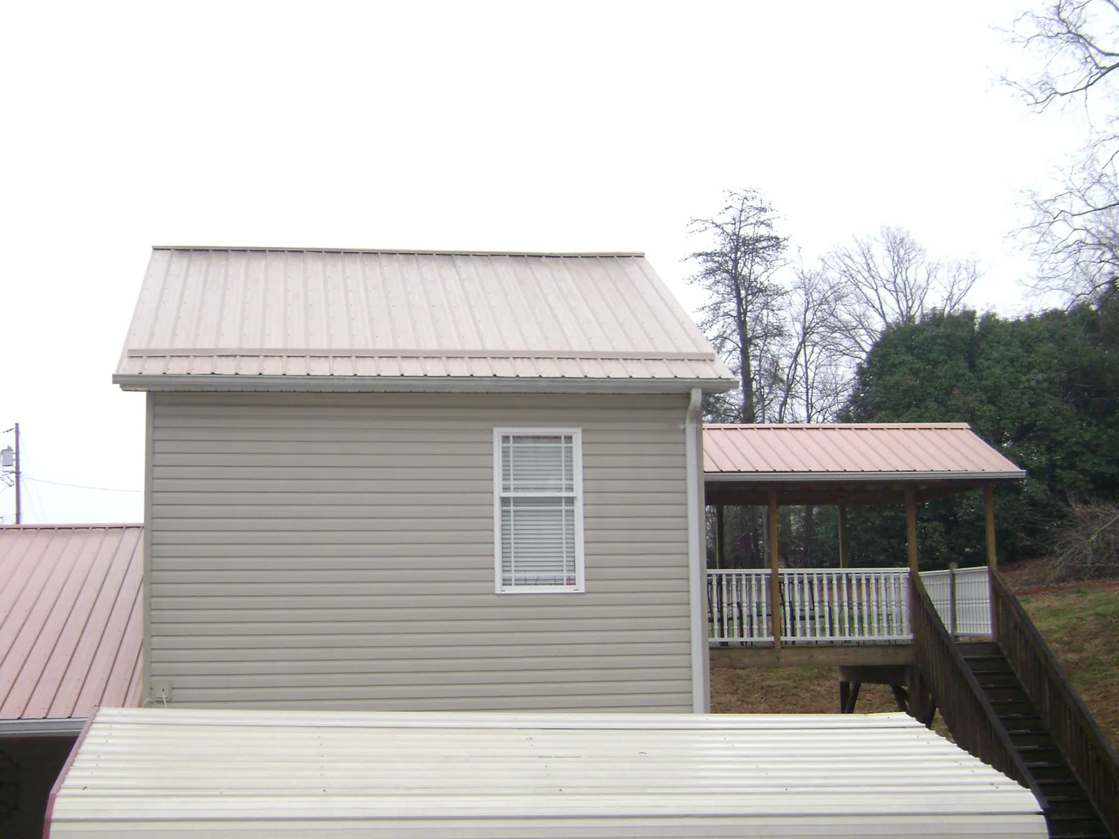 Tan metal roofs on a two story addition and attached porch, from a Roof Replacement job in Cataldo