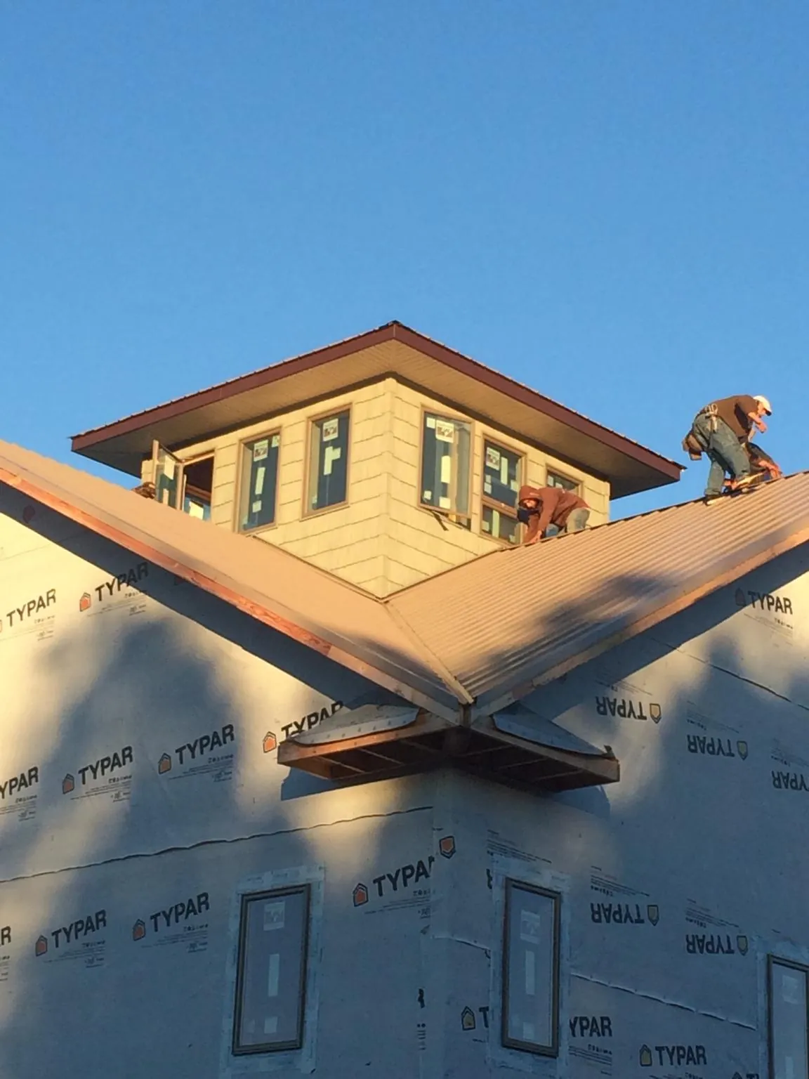 Roofers working around a rooftop cupola on a new metal roof at sunset — Roof Waterproofing in Cataldo by Roofing Brothers